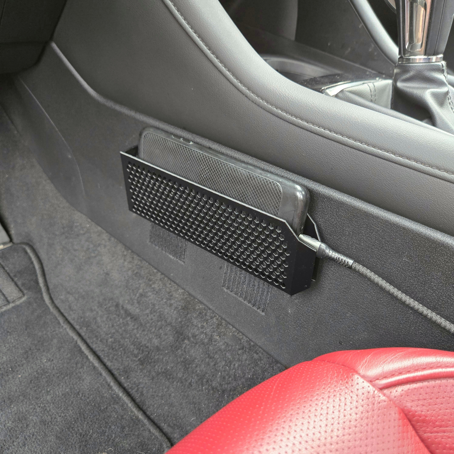 Car interior with a black phone holder attached to the door panel.
