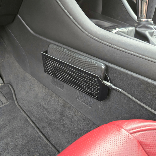 Car interior with a black phone holder attached to the door panel.