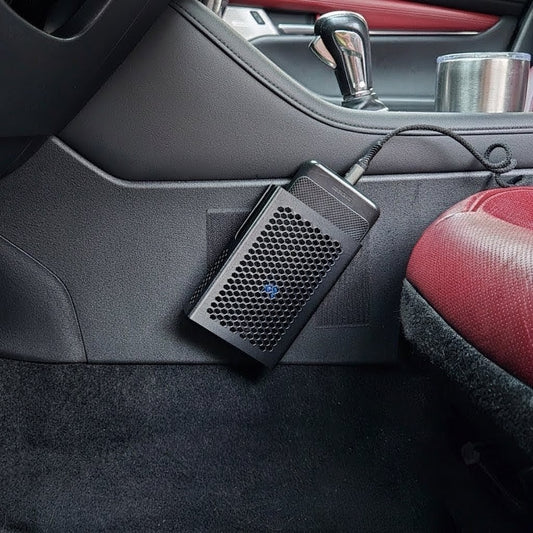 MATERIUM universal top-load phone holder mounted on car console side panel, phone seated in holder with charging cable, red interior