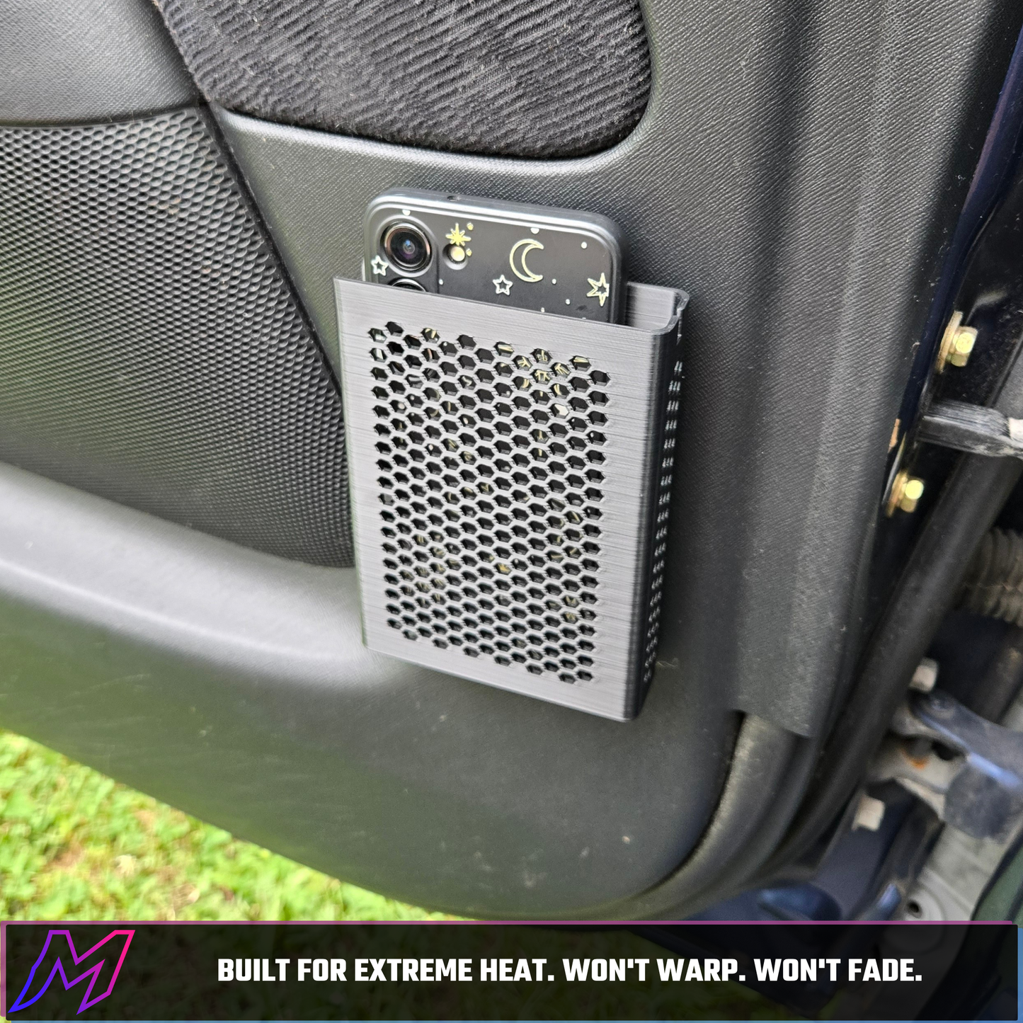 MATERIUM universal phone holder mounted on door panel outdoors, phone loaded, fuchsia bar reads Built for Extreme Heat Won't Warp Won't Fade