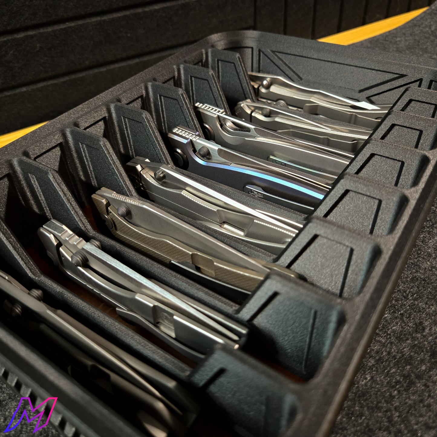 MATERIUM Vanguard Array close-up with large folding knives in individual slots, ribbed matte black exterior