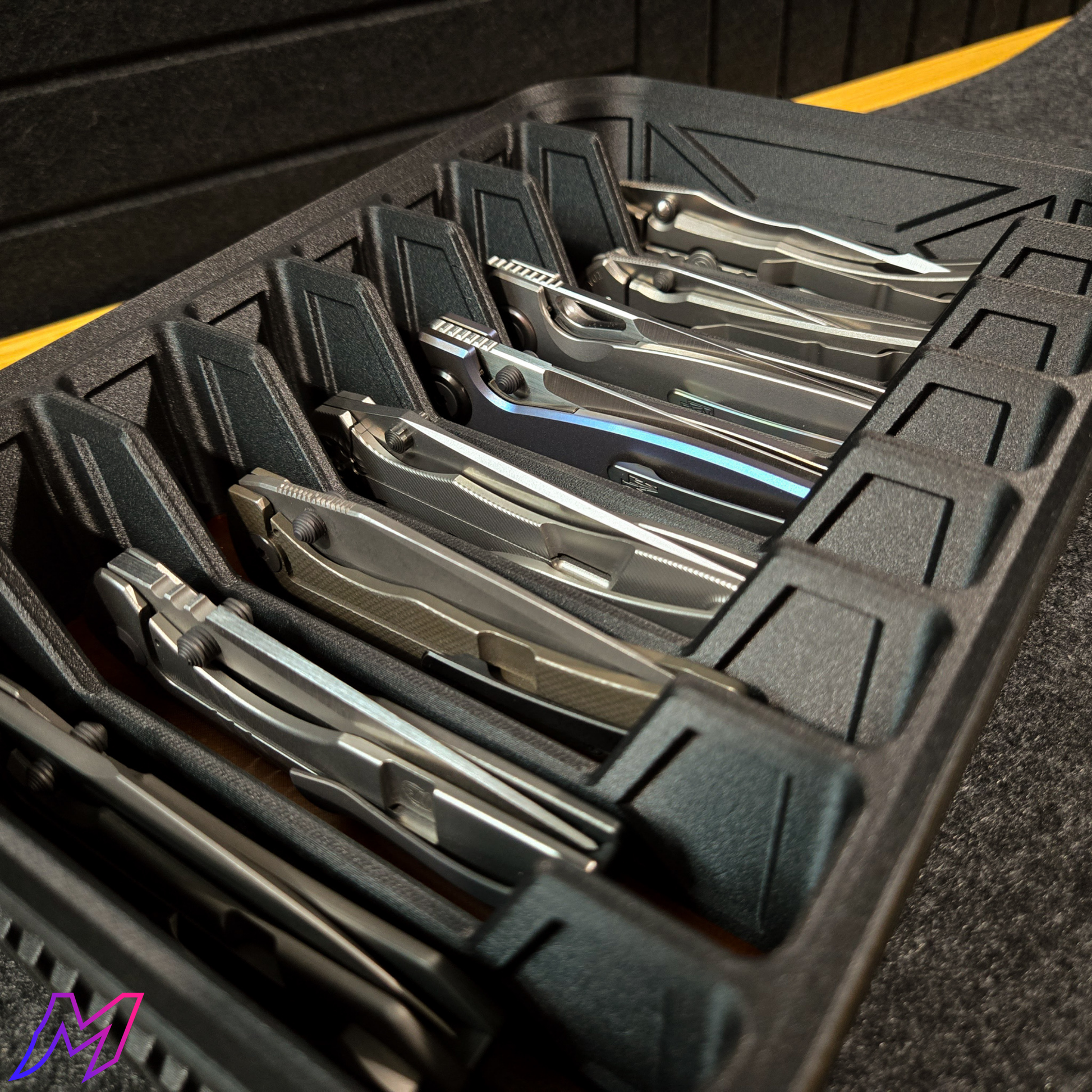 MATERIUM Vanguard Array close-up with large folding knives in individual slots, ribbed matte black exterior