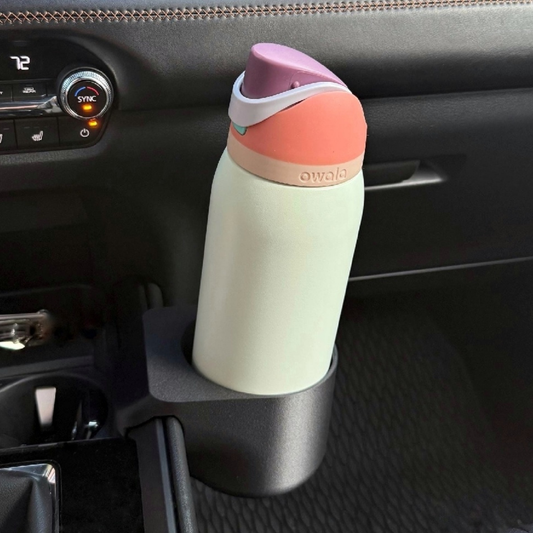 Multicolored water bottle in a car cup holder with 'awala' branding.